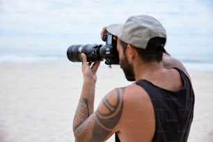 um homem tirando uma foto da praia com uma câmera