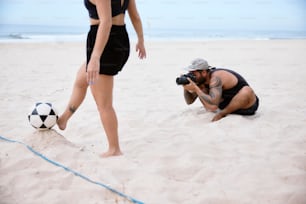 um homem que tira uma foto de uma mulher na praia