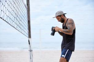 Un homme tenant une caméra près d’un filet de volley-ball