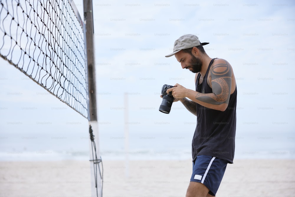 um homem segurando uma câmera perto de uma rede de voleibol