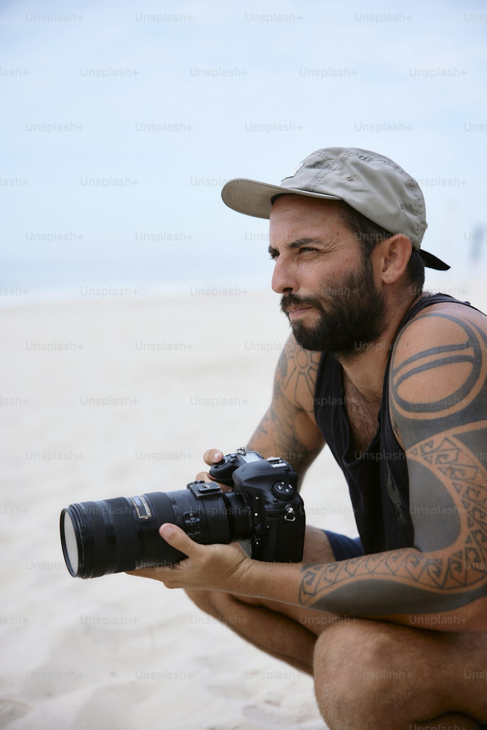 Un uomo con un tatuaggio sul braccio che tiene una macchina fotografica
