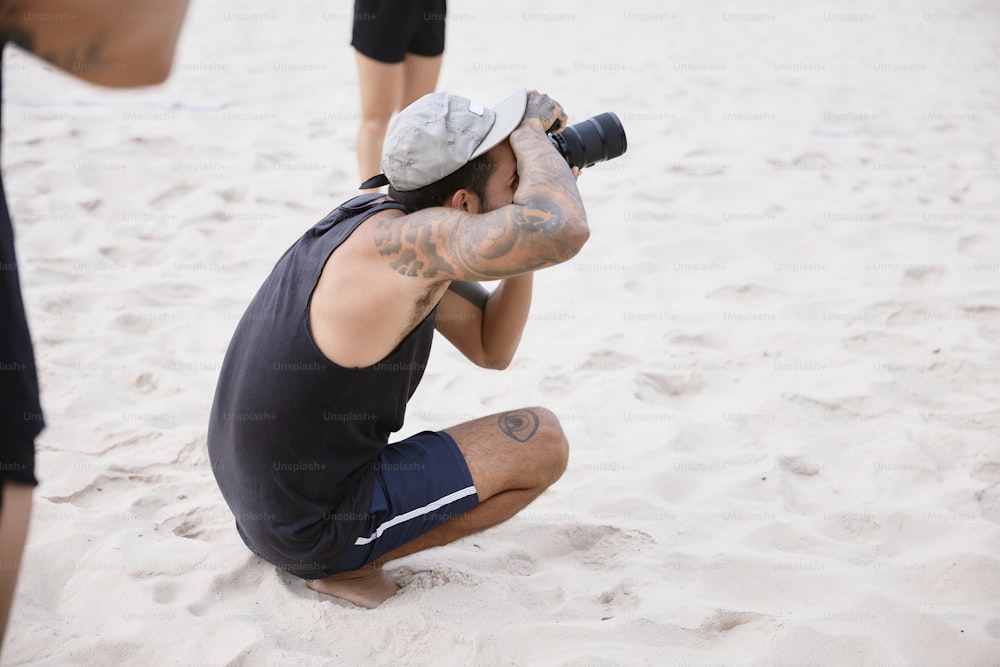 Ein Mann sitzt mit einer Kamera im Sand