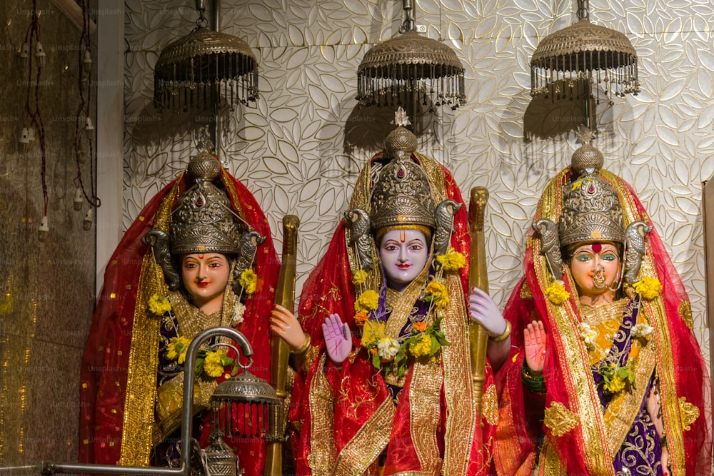 Tres estatuas de deidades hindúes vestidas con atuendos tradicionales