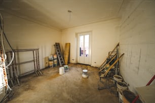 una habitación con una escalera, cubos y latas de pintura