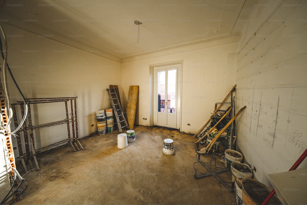 a room with a ladder, buckets and paint cans