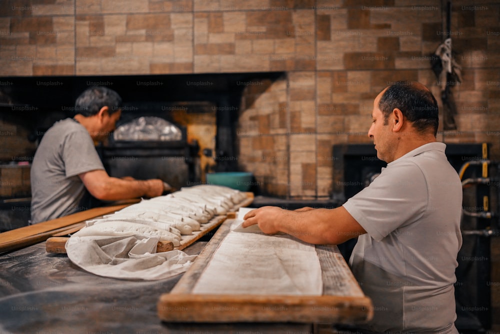 dois homens que trabalham em uma padaria fazendo pão