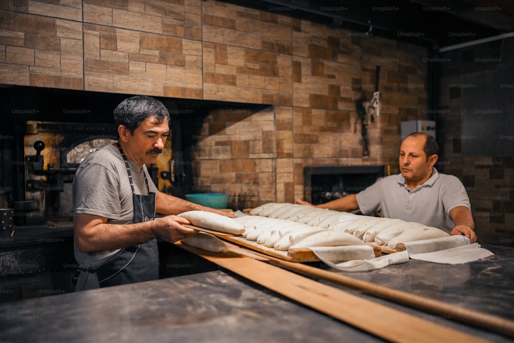 dois homens que trabalham em uma padaria fazendo pão