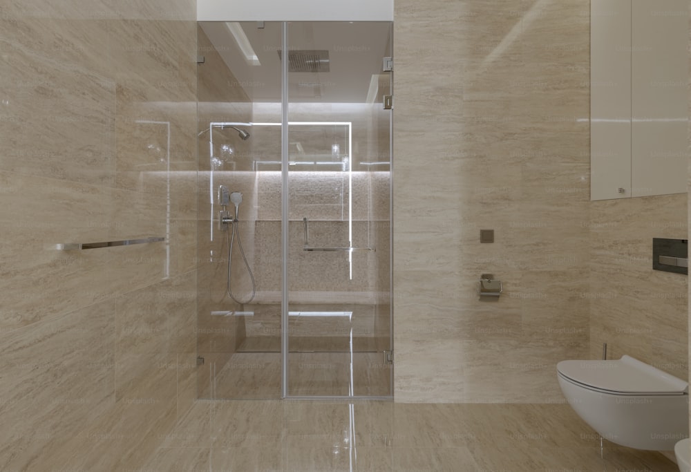 uma casa de banho com uma porta de duche de vidro e um WC