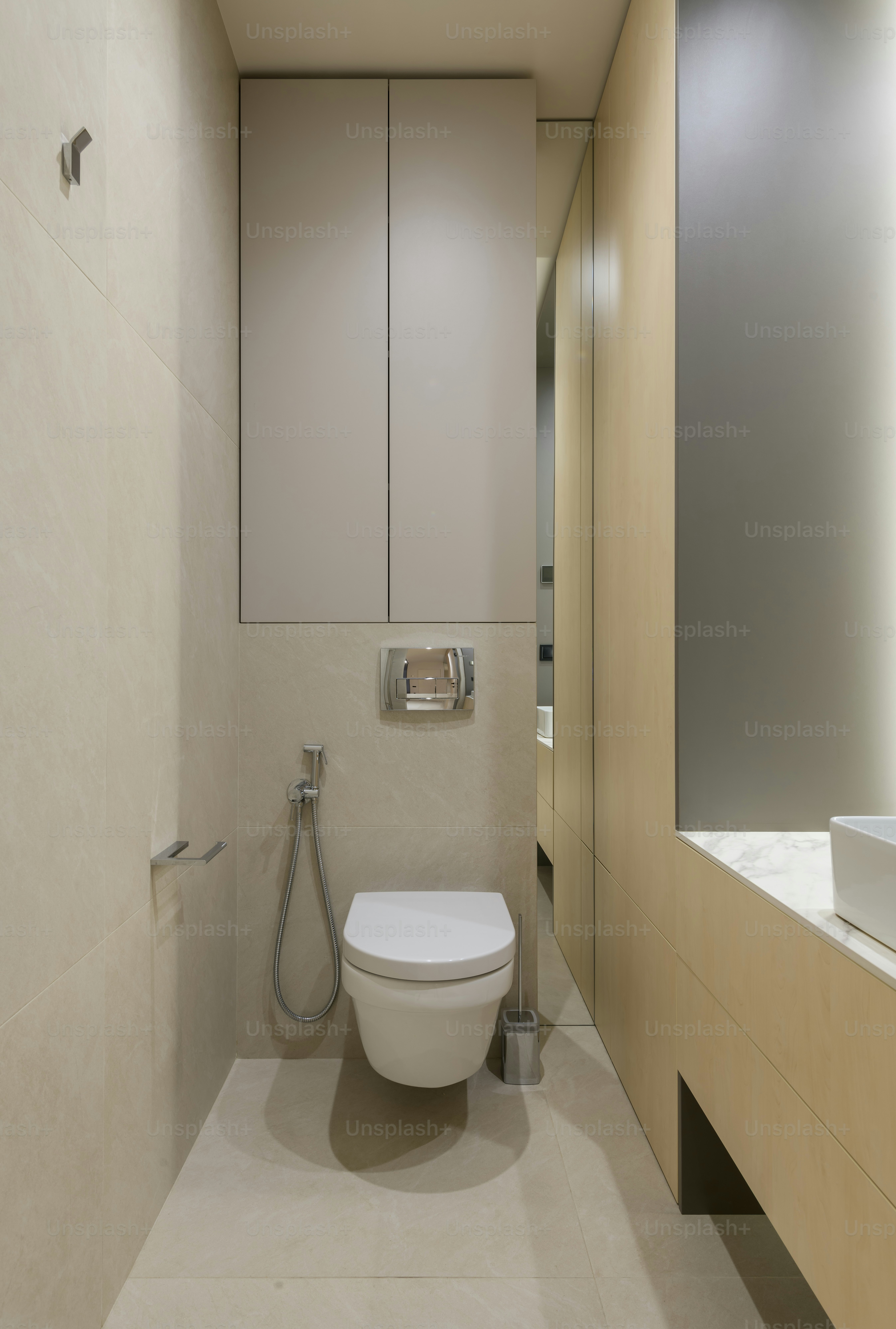 A white toilet sitting in a bathroom next to a sink photo – Wc Image on ...