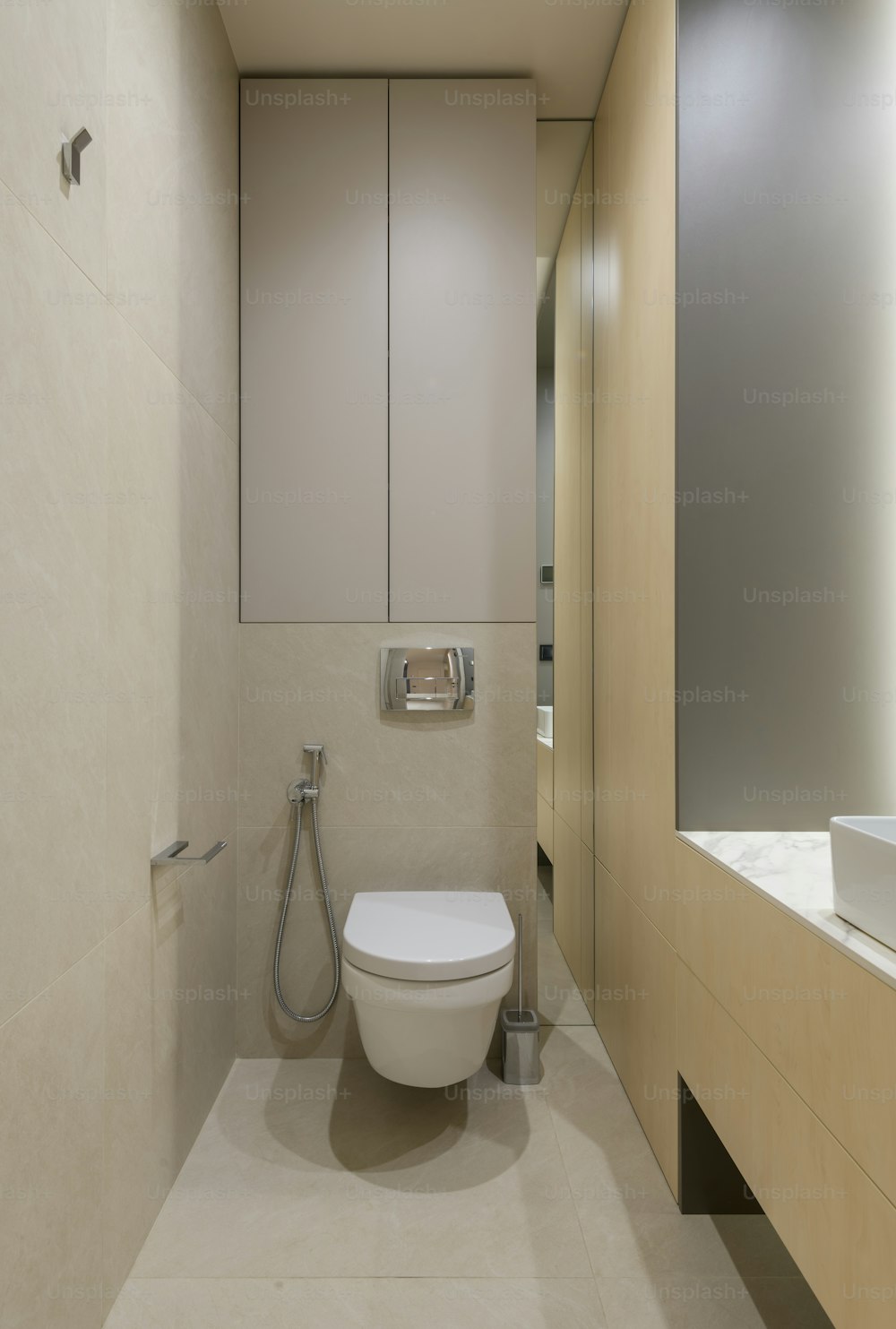 une toilette blanche assise dans une salle de bain à côté d’un lavabo