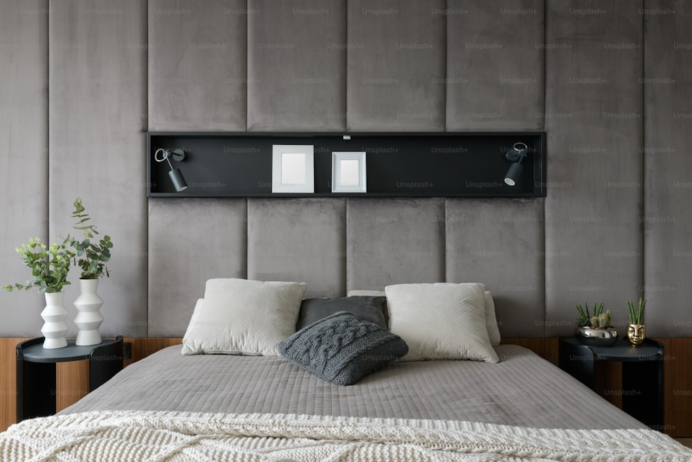 uma cama com cabeceira cinza e travesseiros brancos