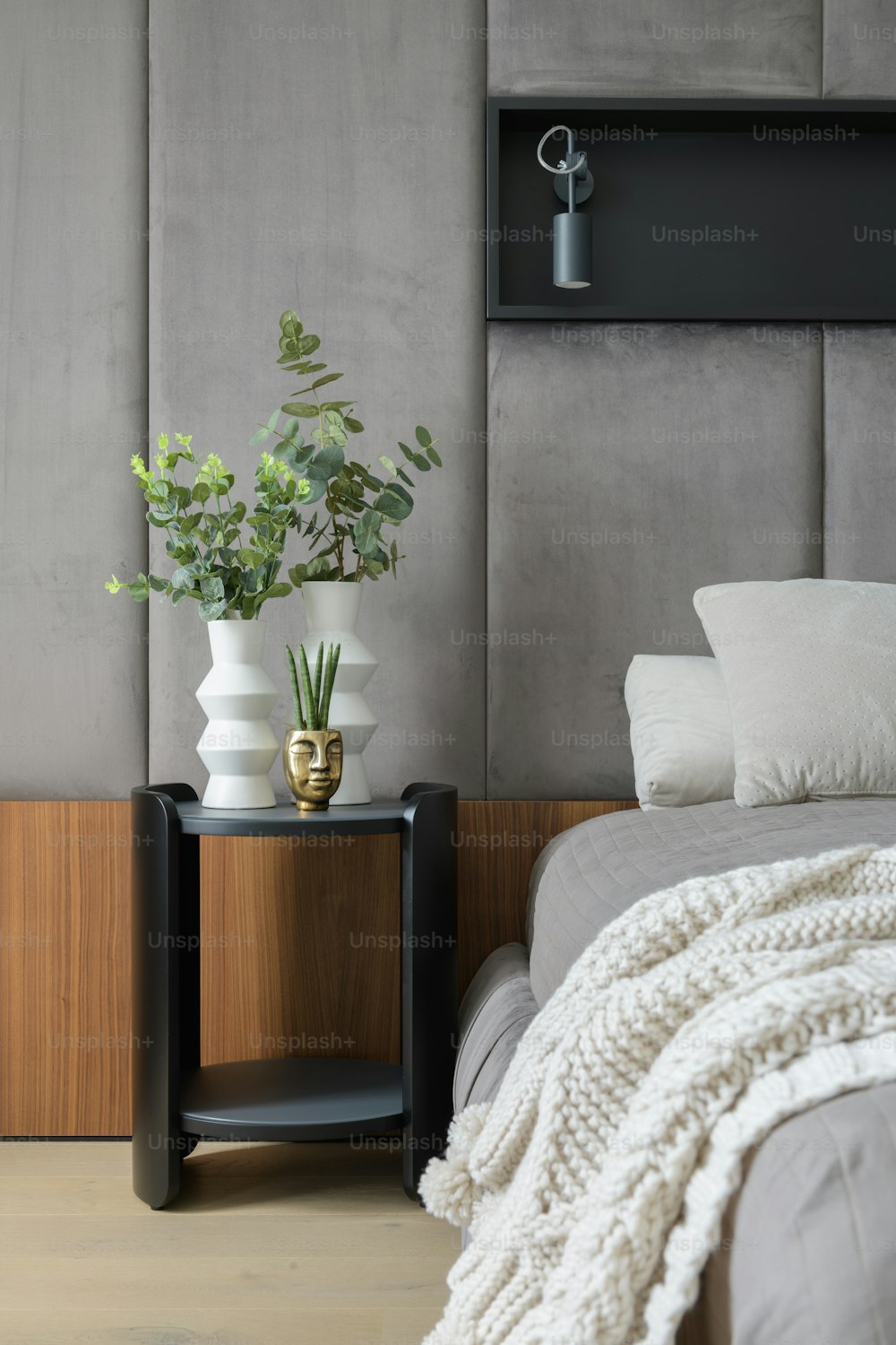 um quarto com uma cama, mesa de cabeceira e uma planta