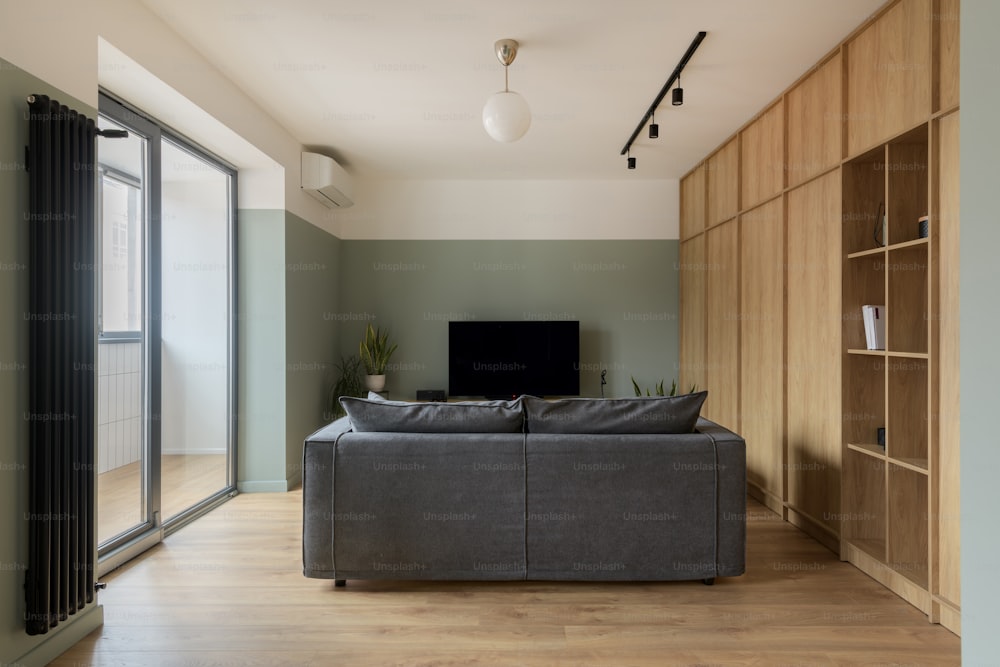 Un soggiorno con divano grigio e TV a schermo piatto