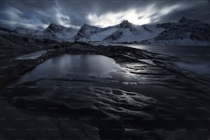 a body of water surrounded by mountains under a cloudy sky