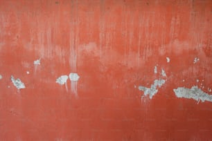 uma parede vermelha com tinta descascada sobre ela