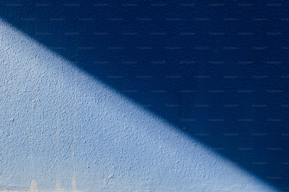 una pared azul con la sombra de un reloj