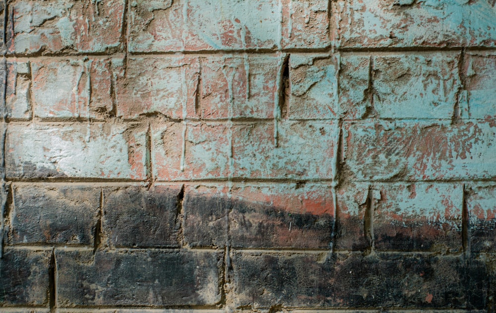 uma parede de tijolos com uma tinta vermelha e azul sobre ela
