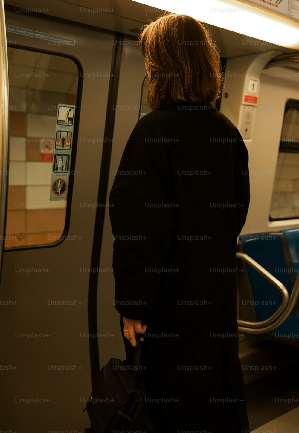 a woman in a black coat waiting for a train