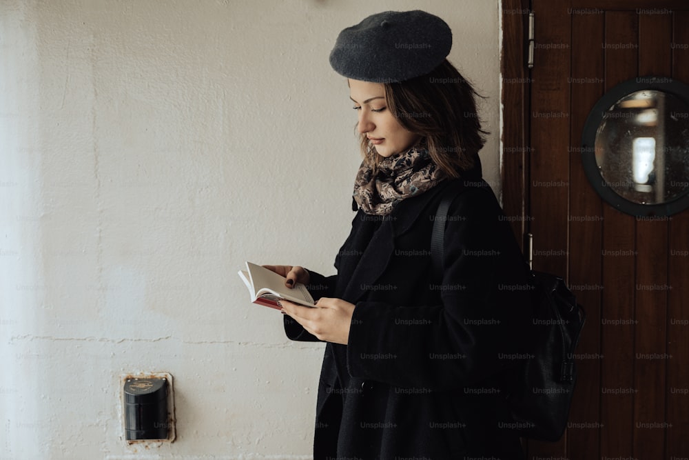 a woman in a black coat is reading a book