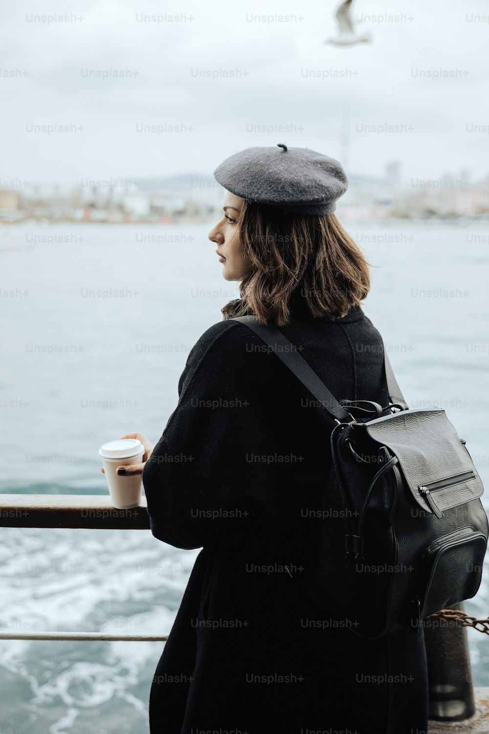 コーヒーカップを手に桟橋に立っている女性
