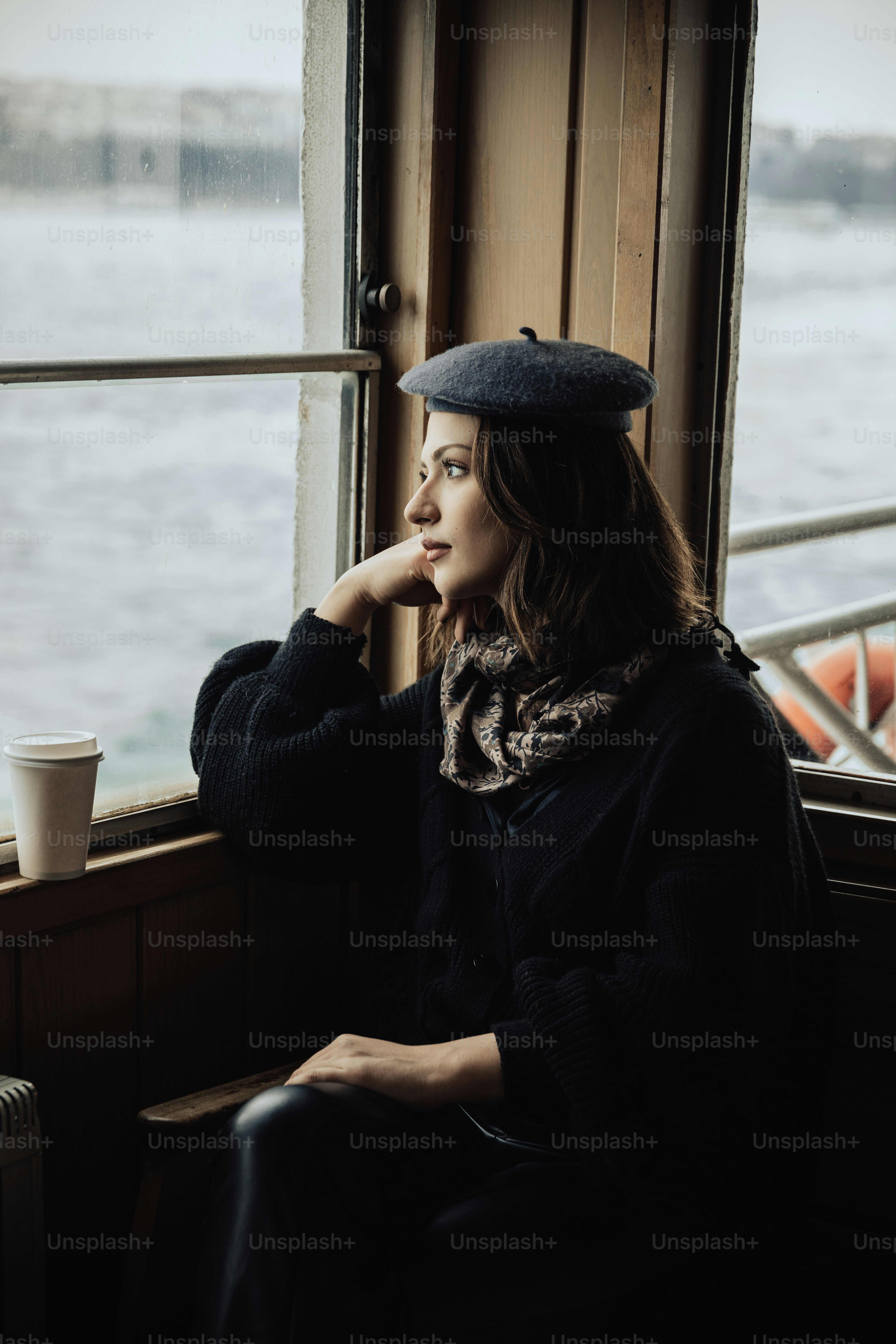 a woman sitting on a window sill next to a cup of coffee