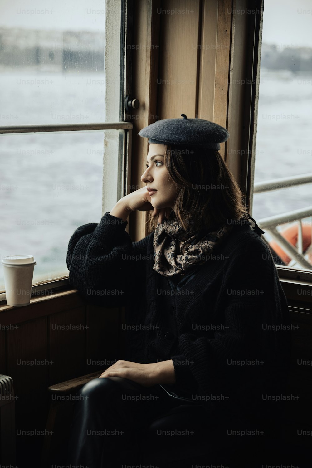 a woman sitting on a window sill next to a cup of coffee