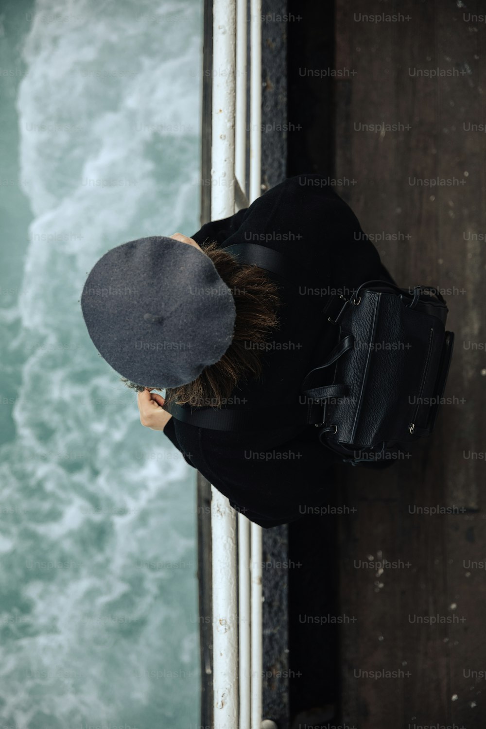 a person wearing a hat looking down at the water