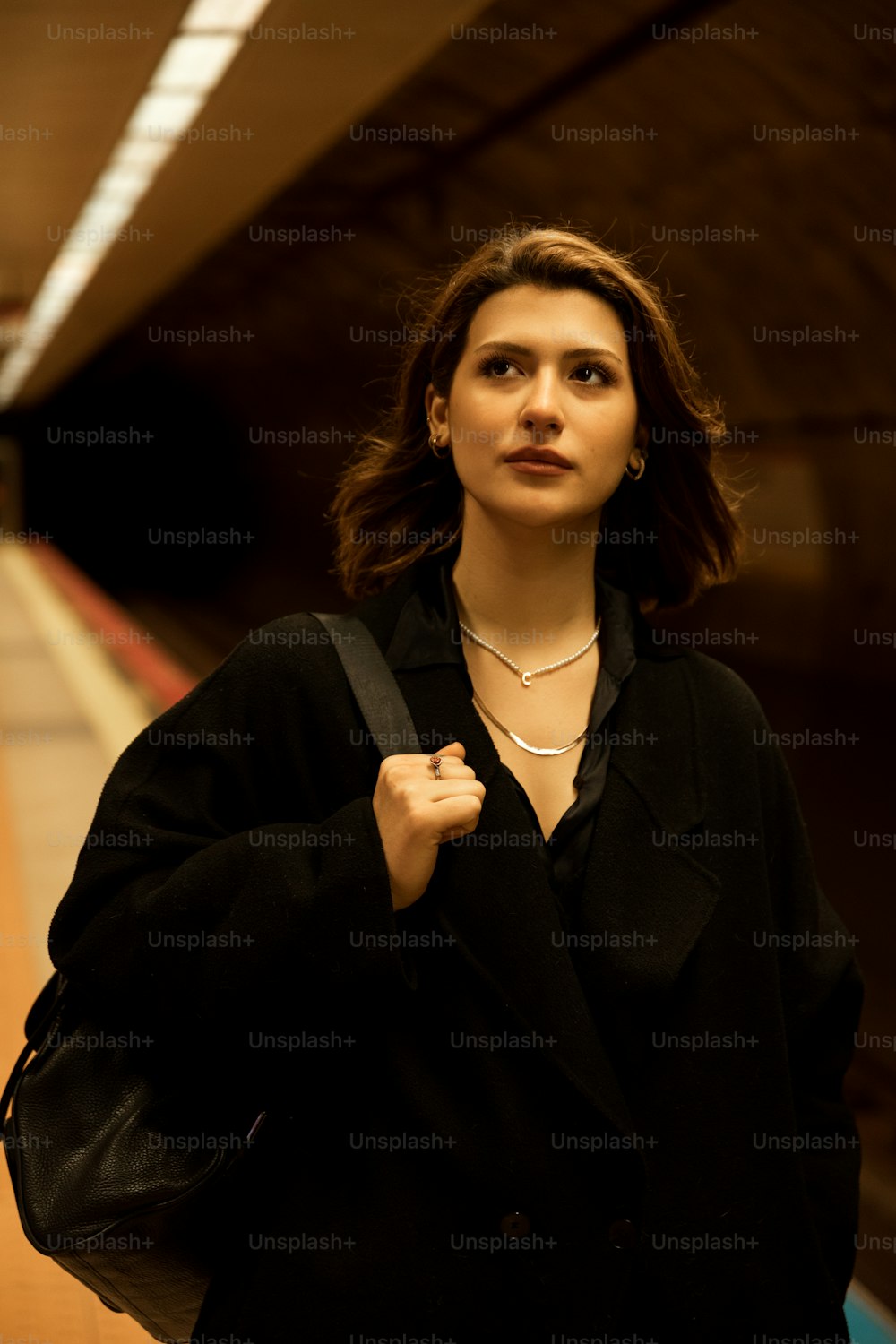 a woman standing in a subway station with her hand on her shoulder