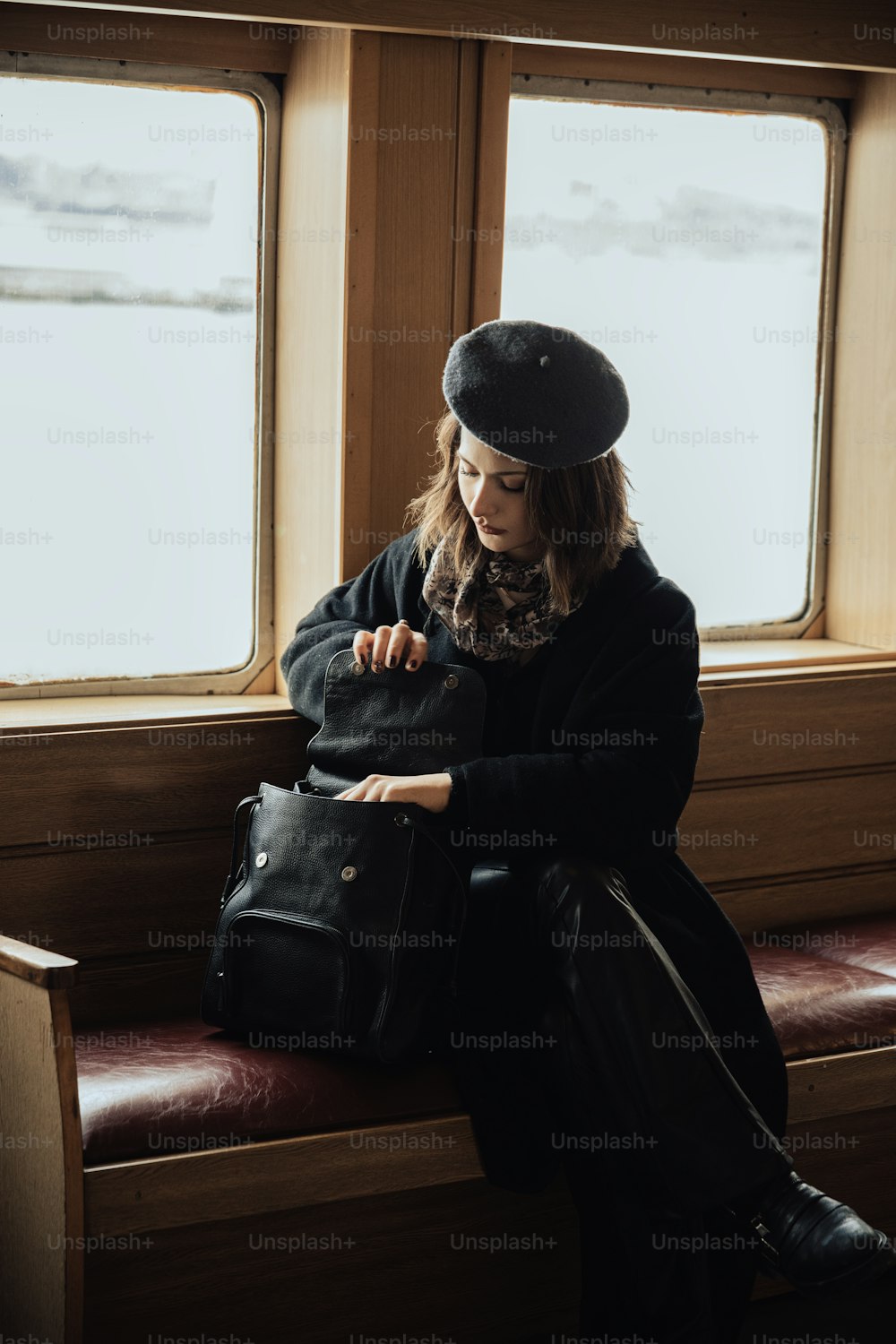 Una mujer sentada en un banco frente a una ventana