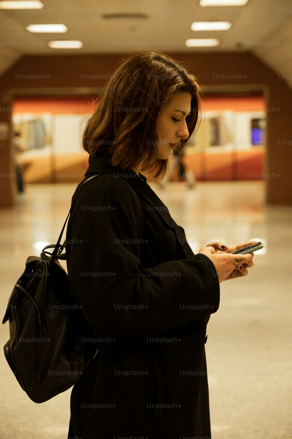 Une femme debout dans un immeuble regardant son téléphone portable