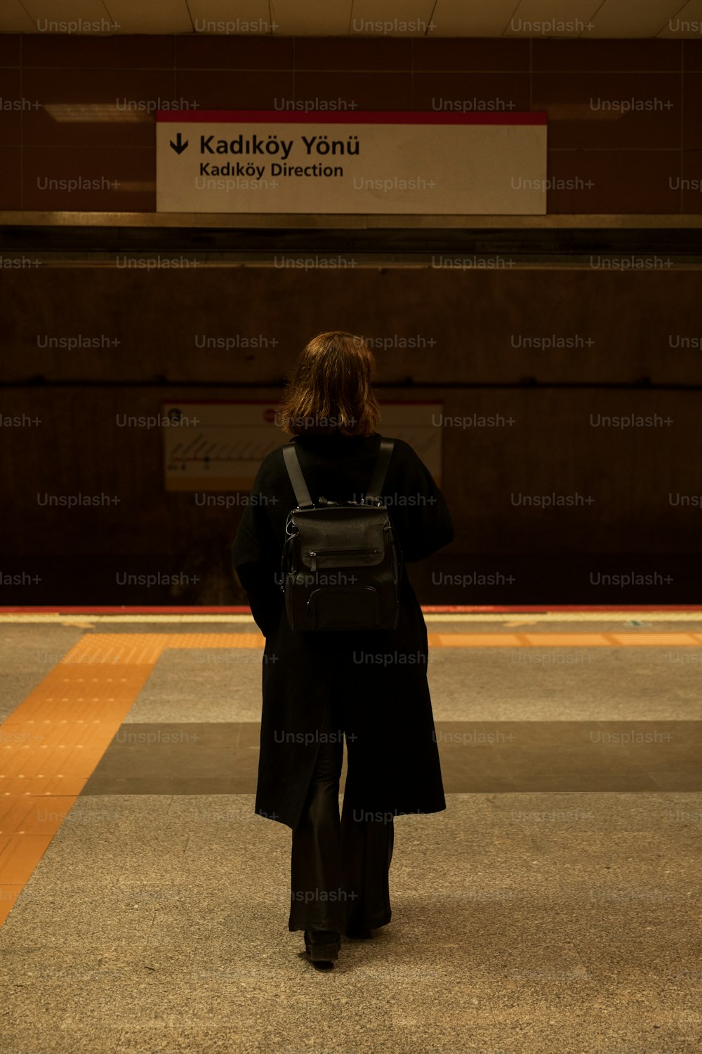 a woman in a black coat and a black backpack