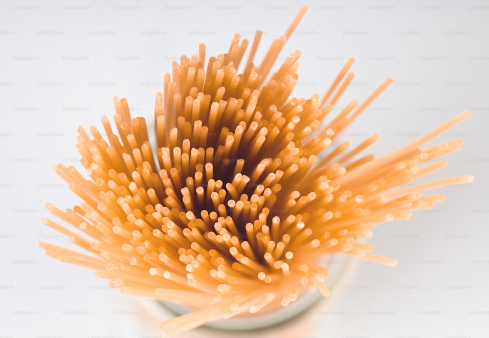 a close up of a vase with a bunch of straws in it