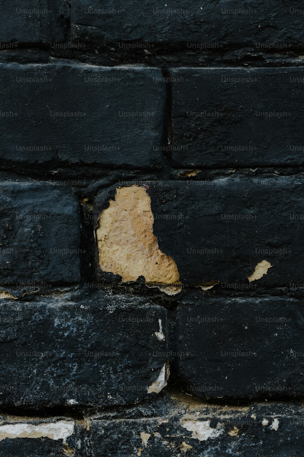 un mur de briques noires avec un morceau de papier qui en sort