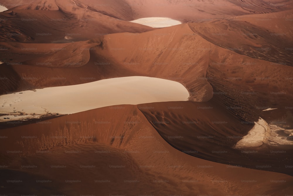 an aerial view of a desert with a lake in the middle of it