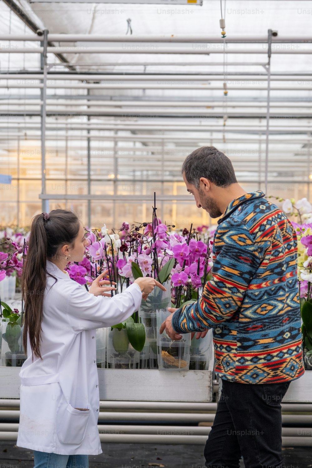 a man and a woman are standing in a greenhouse