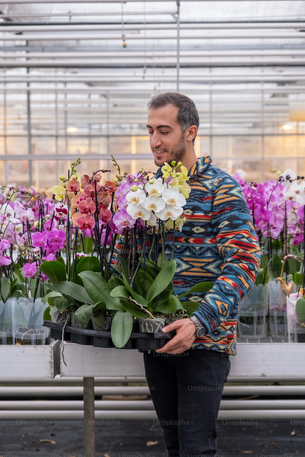 a man standing next to a bunch of flowers