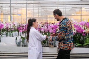 a man and a woman standing in front of flowers