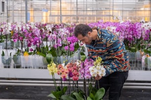 a man kneeling down next to a bunch of flowers