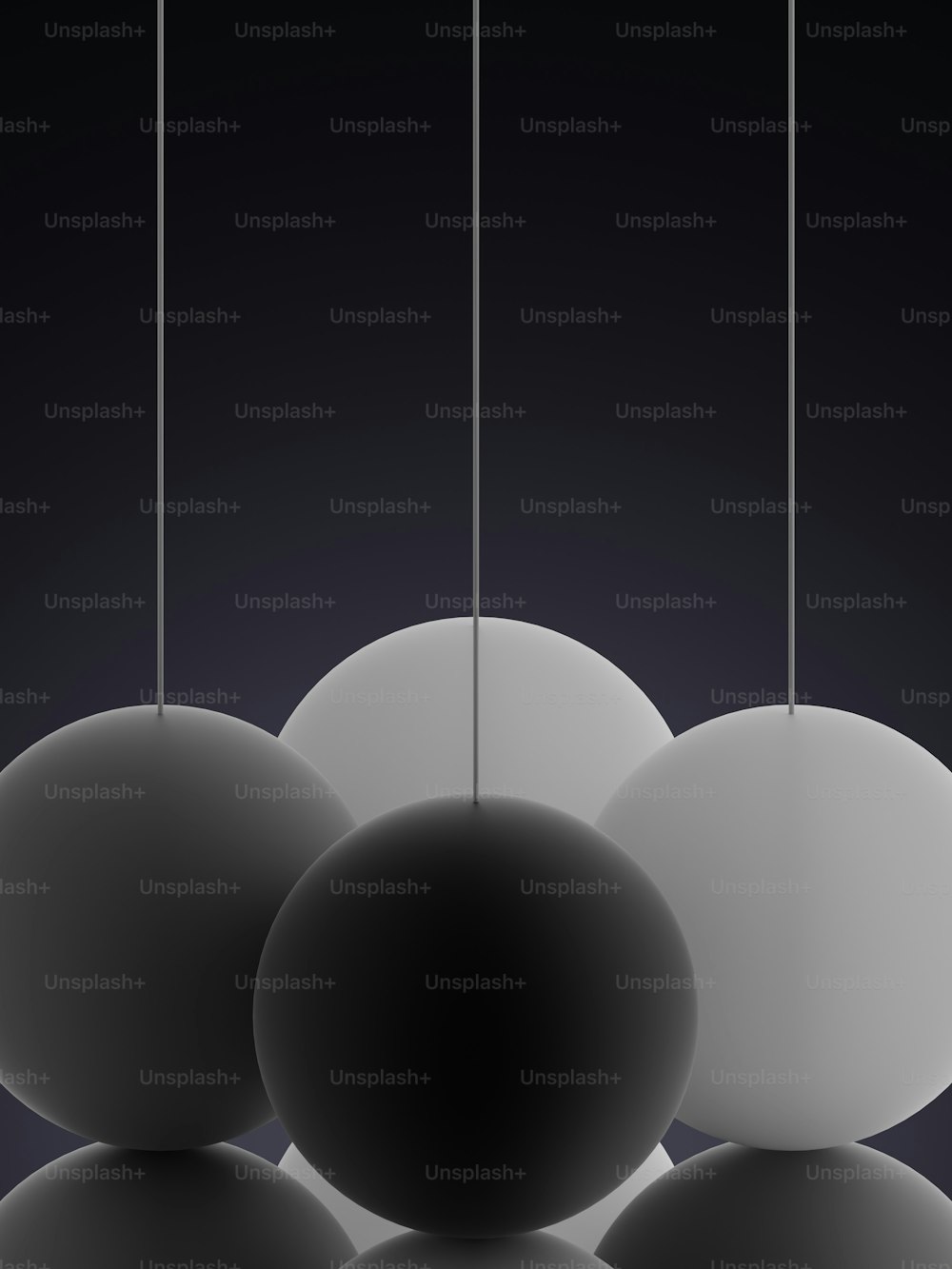 Une photo en noir et blanc de trois balles suspendues à des ficelles