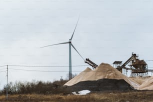 a large pile of dirt next to a wind turbine