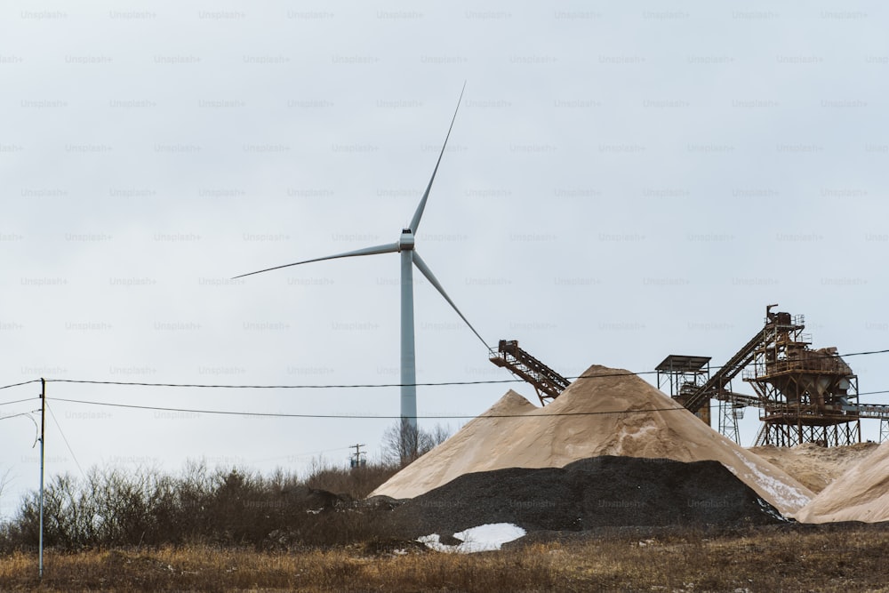 a large pile of dirt next to a wind turbine