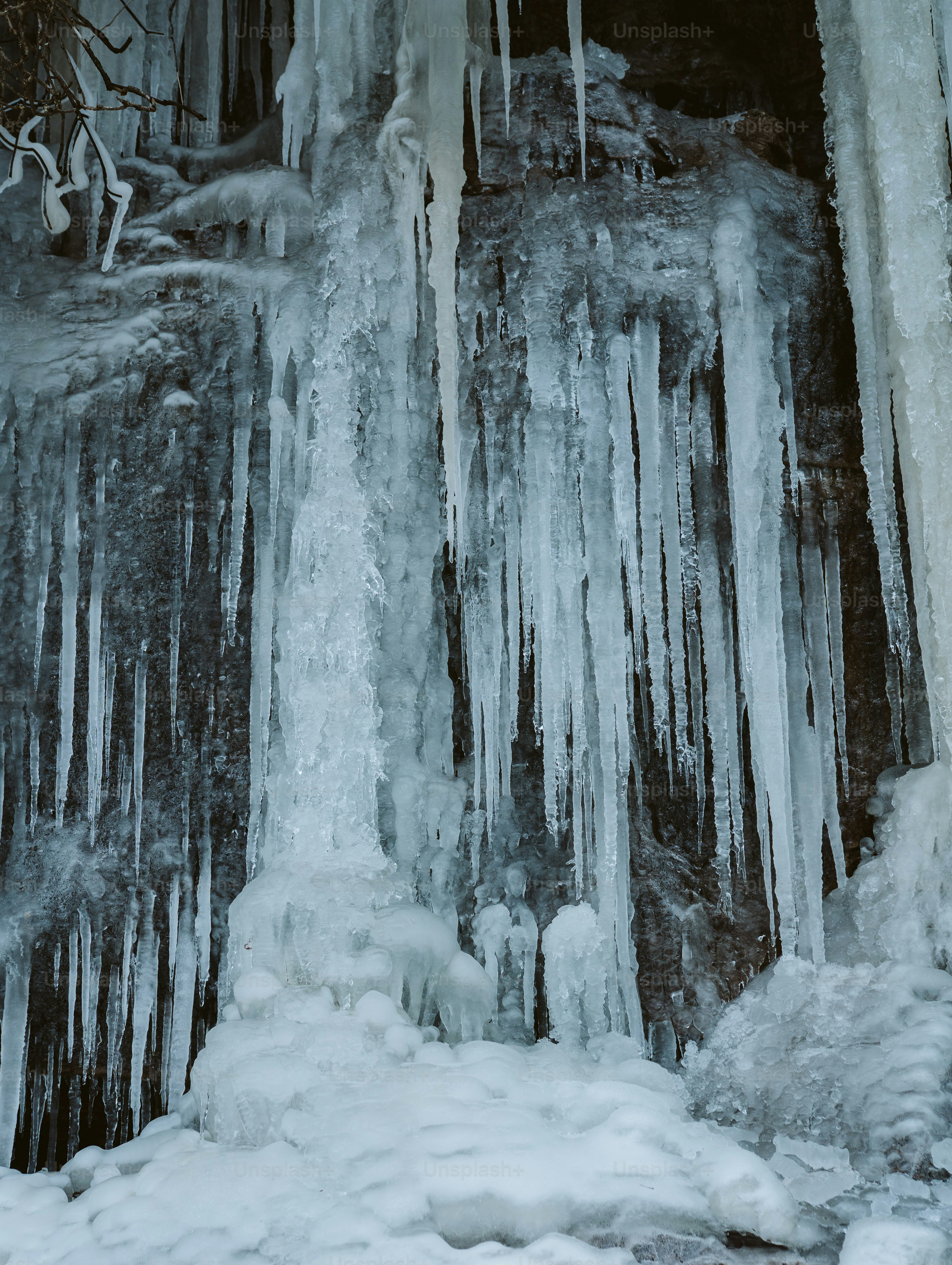 icicles are hanging from the side of a waterfall