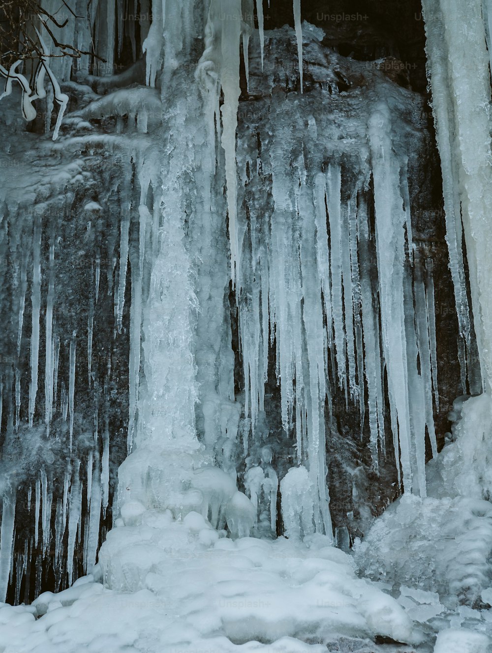 icicles are hanging from the side of a waterfall
