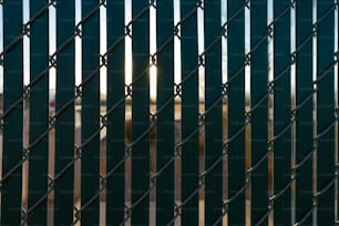 the sun is shining through a chain link fence