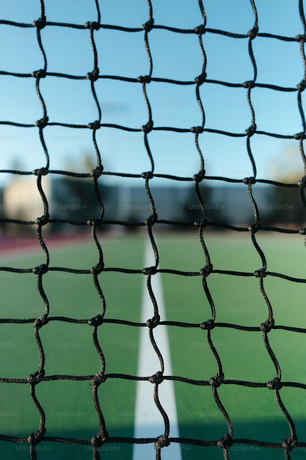a close up of a tennis net with a tennis court in the background