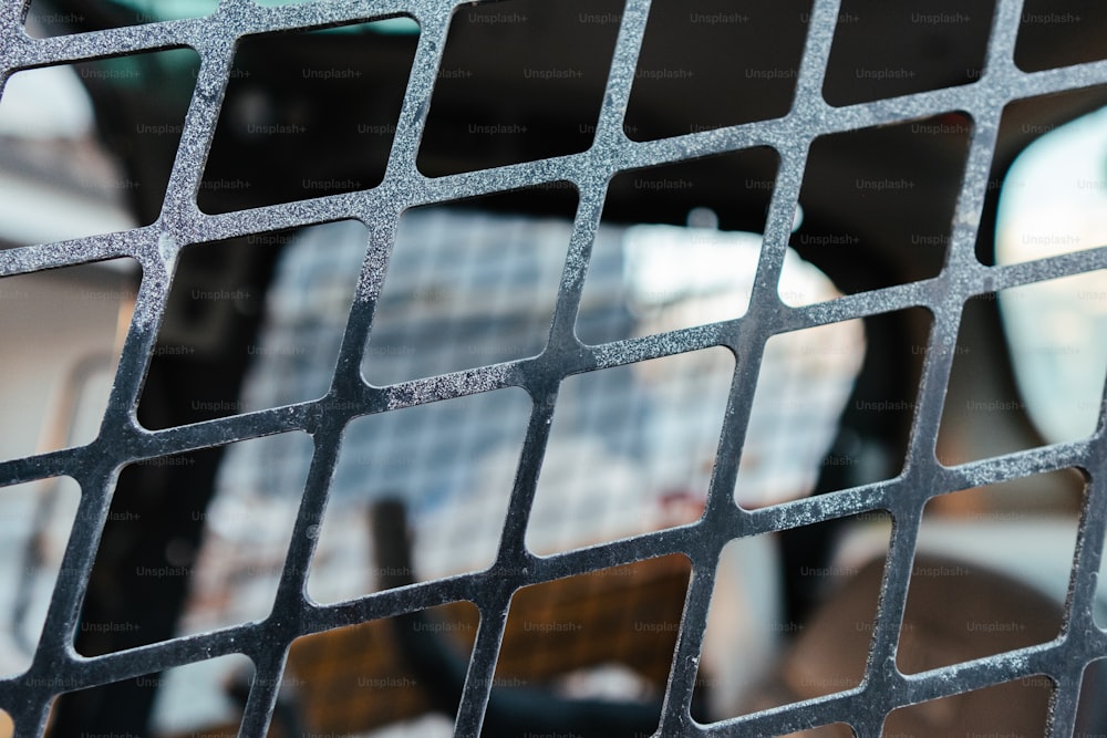 a close up of a metal grate with a building in the background