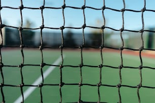 Ein Tennisplatz ist durch ein Netz gesehen