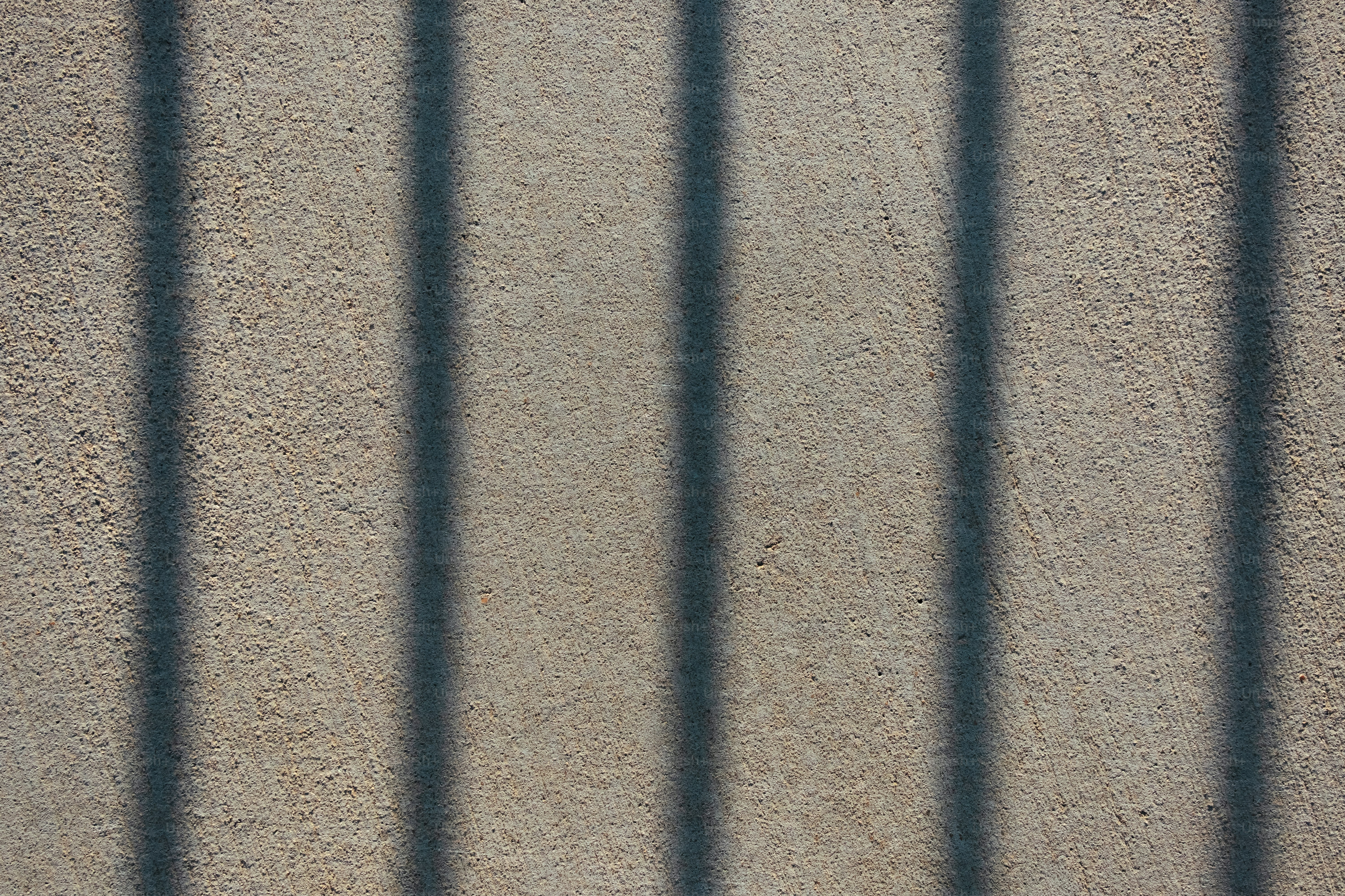 the shadow of a fence on a concrete wall