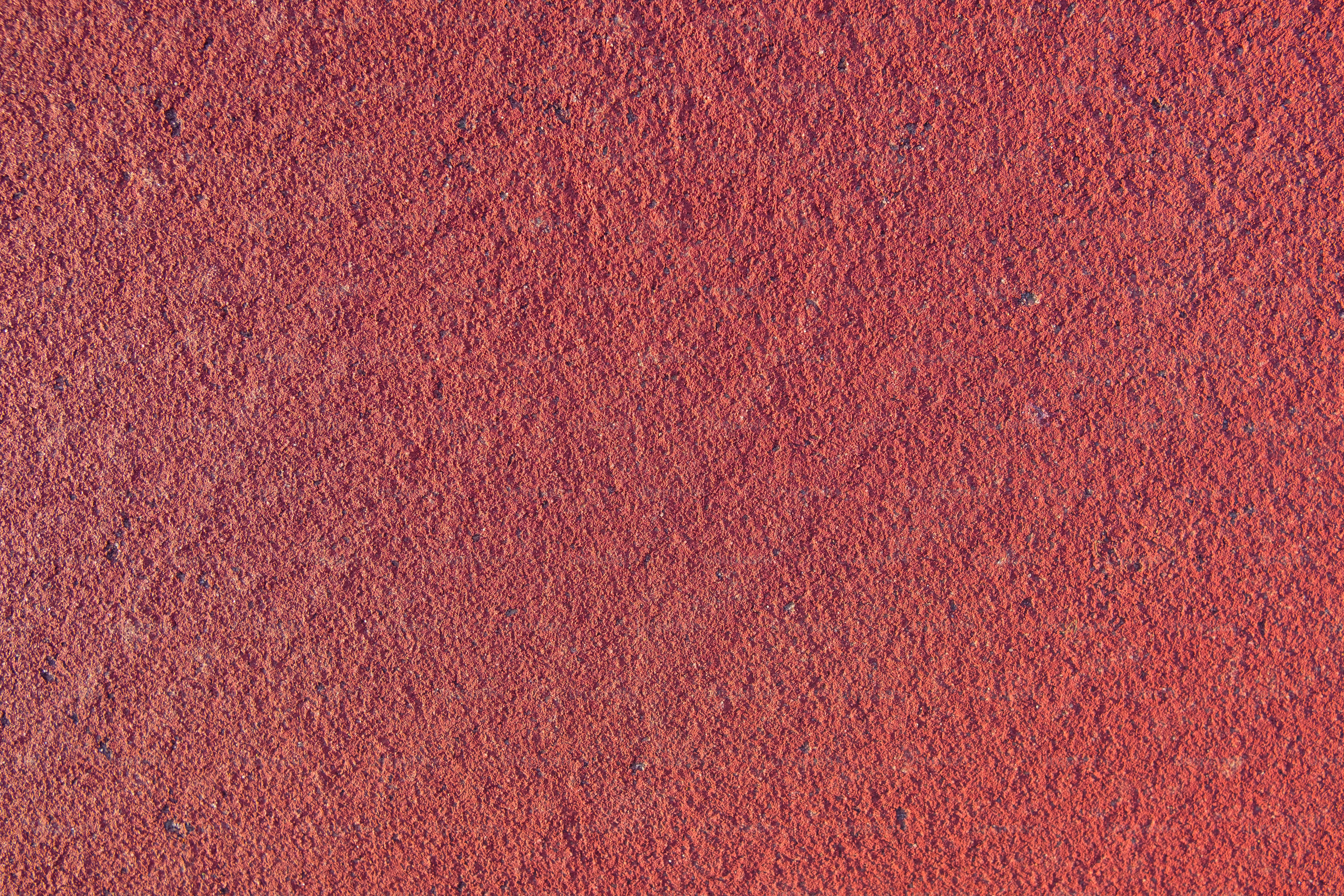 a close up of a red wall with a small patch of dirt