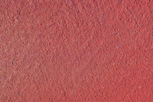 a close up of a red wall with a small patch of dirt